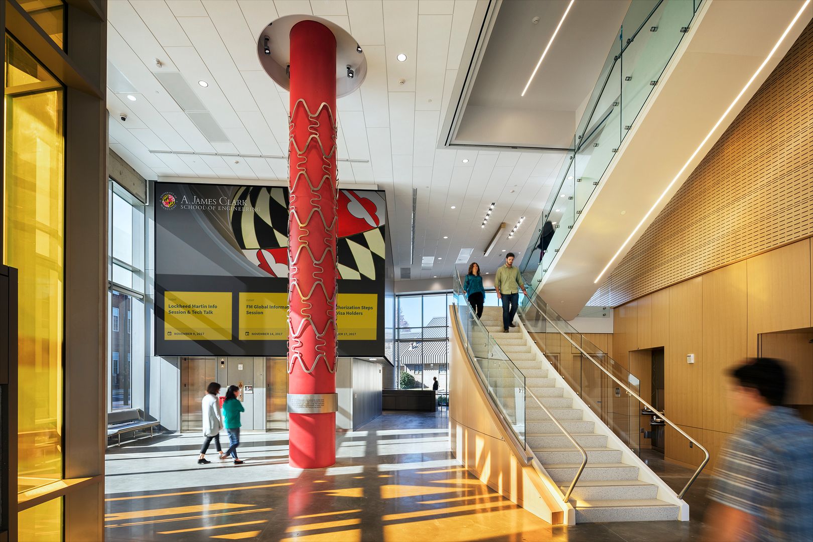 Well-lit entryway of Clark Hall with central artwork and Maryland flag in the background.