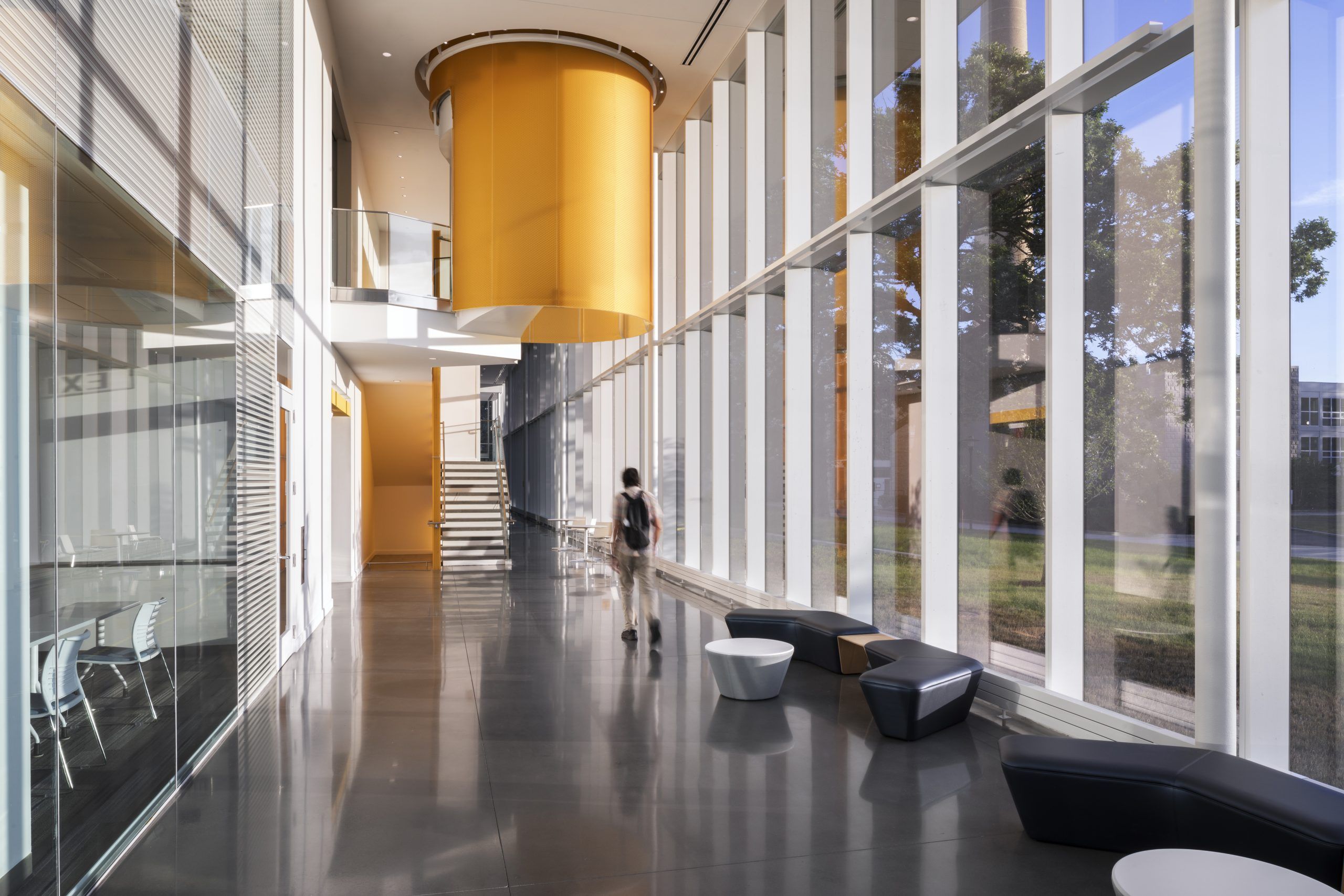 Student walks through open hallway past a staircase