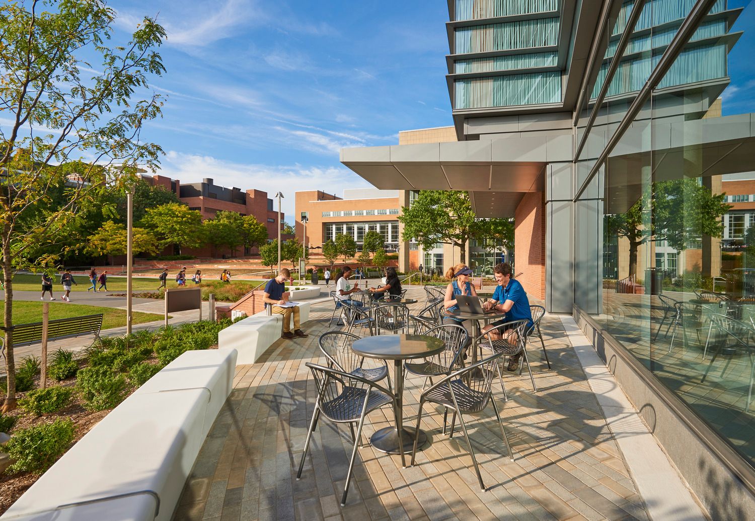 Two students sitting in outdoor patio area overlooking landscaped campus green