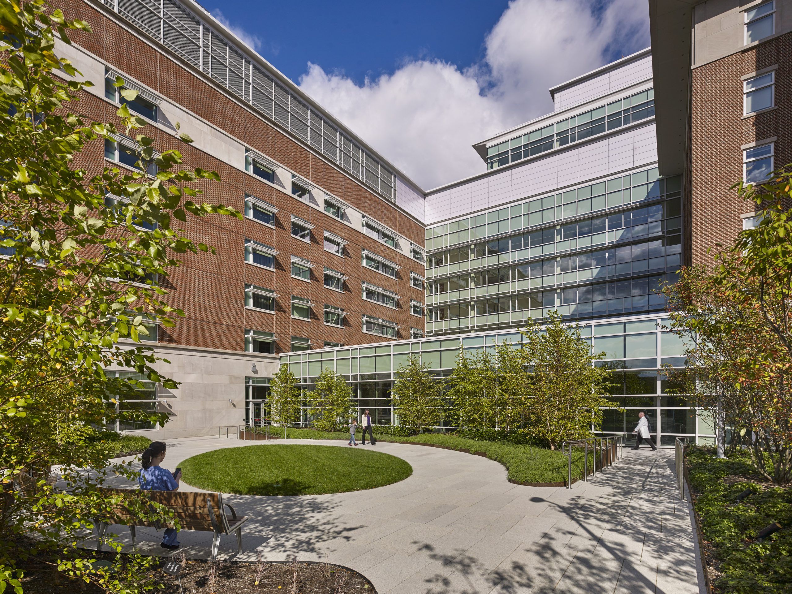 Circular pathway with a mowed grass center, overlooked by hospital patient windows