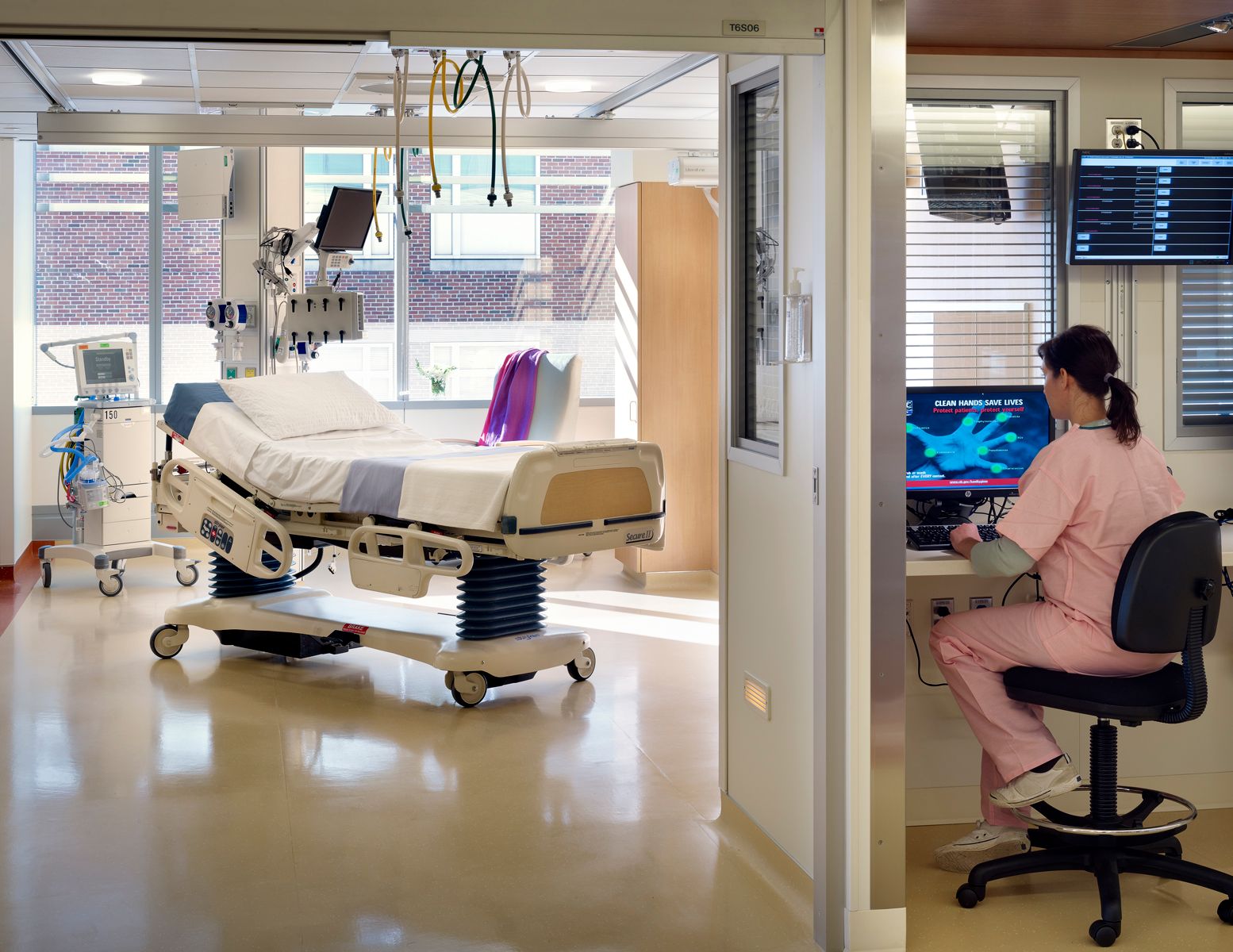 External nurses' station looking into a patient room with large window and medical equipment