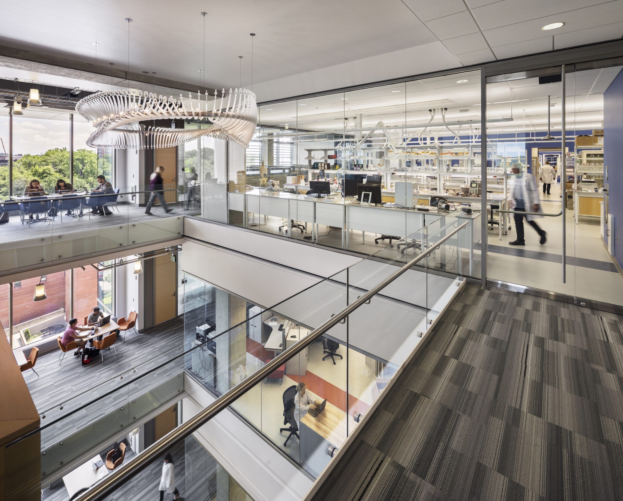 Central building well surrounded by carpeted walkways with glass dividers and natural light