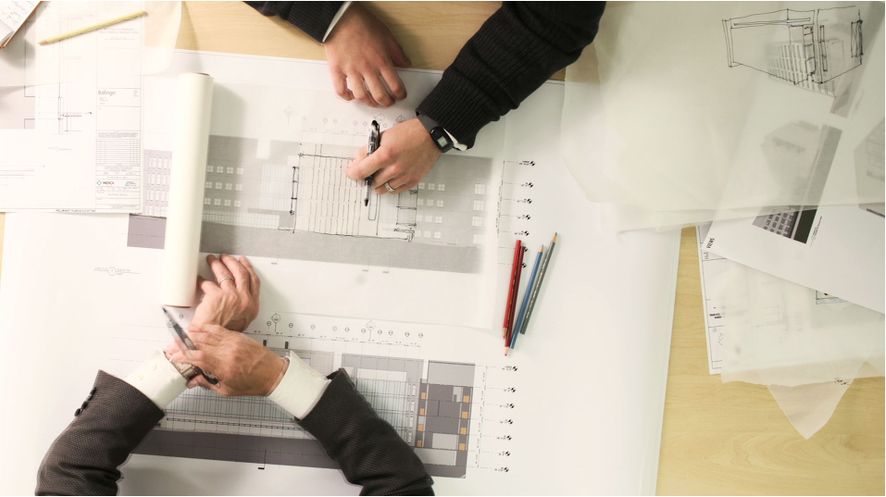 Two people tracing construction drawings