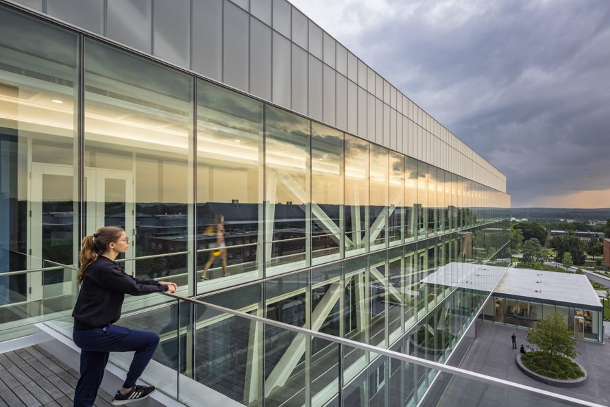 A student on a balcony at the Fascitelli Center for Advanced Engineering looking out over the building